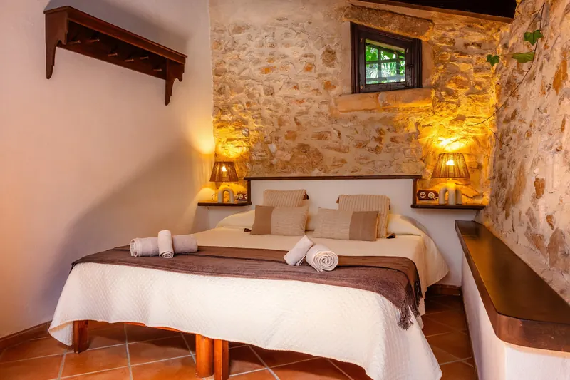 Dormitorio con pared de piedra y lámparas cálidas
